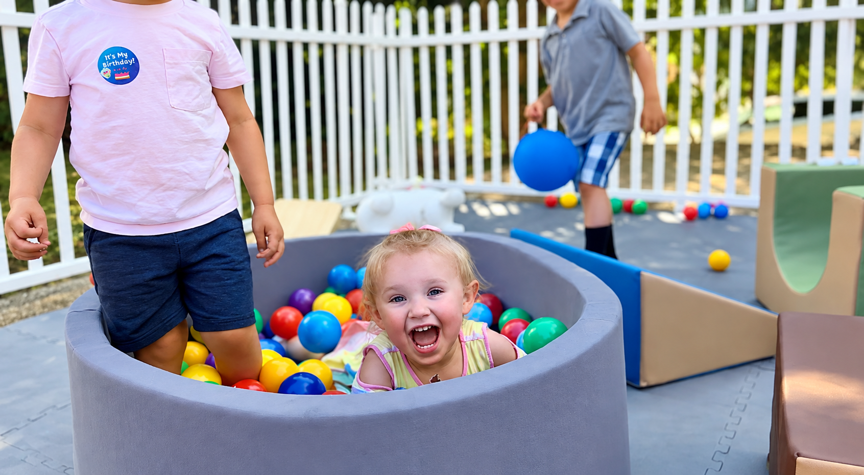 Girl laughing in a ball pit at an outdoor birthday celebration
