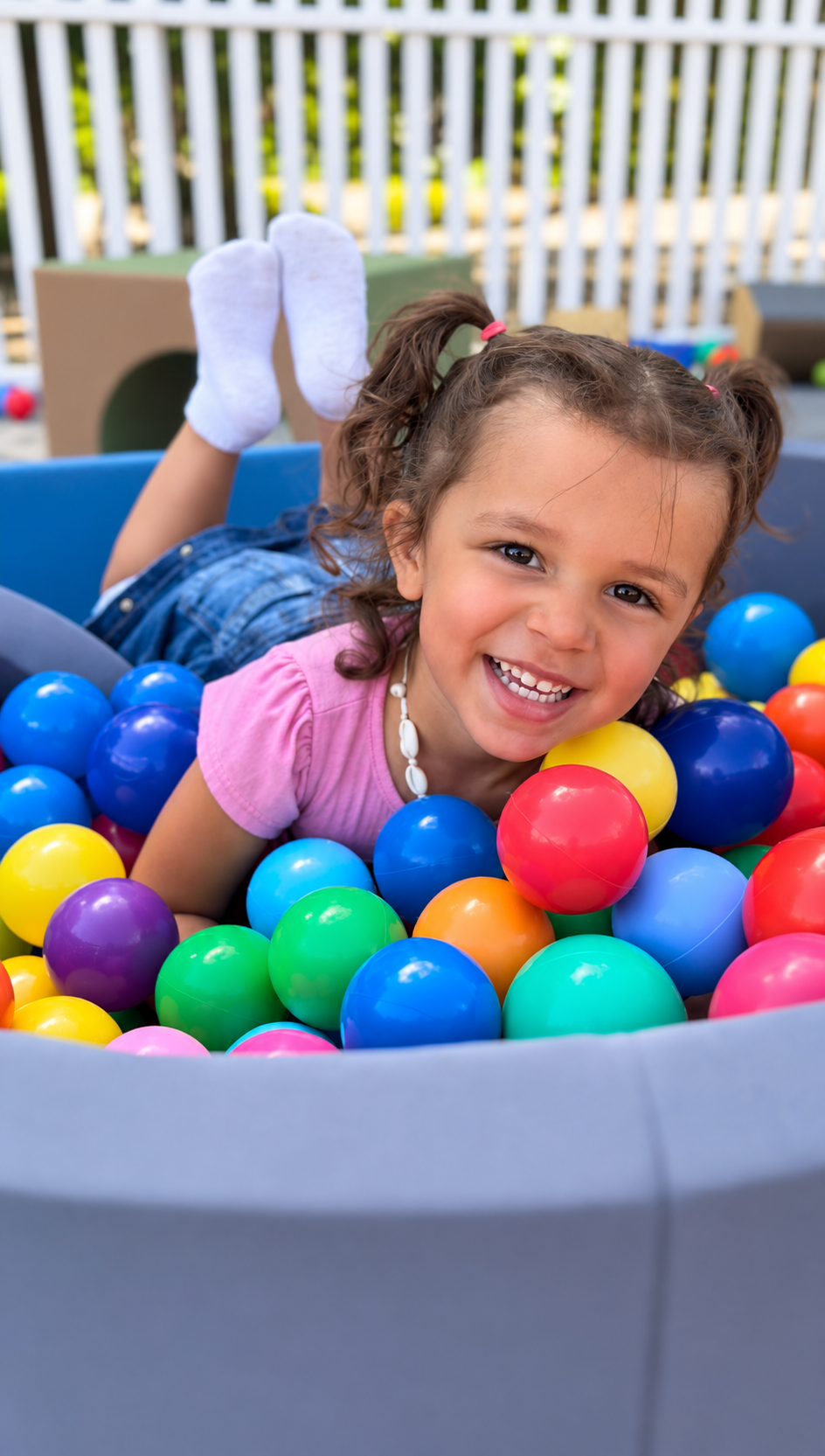 Girl playing in a round ball pit outdoors