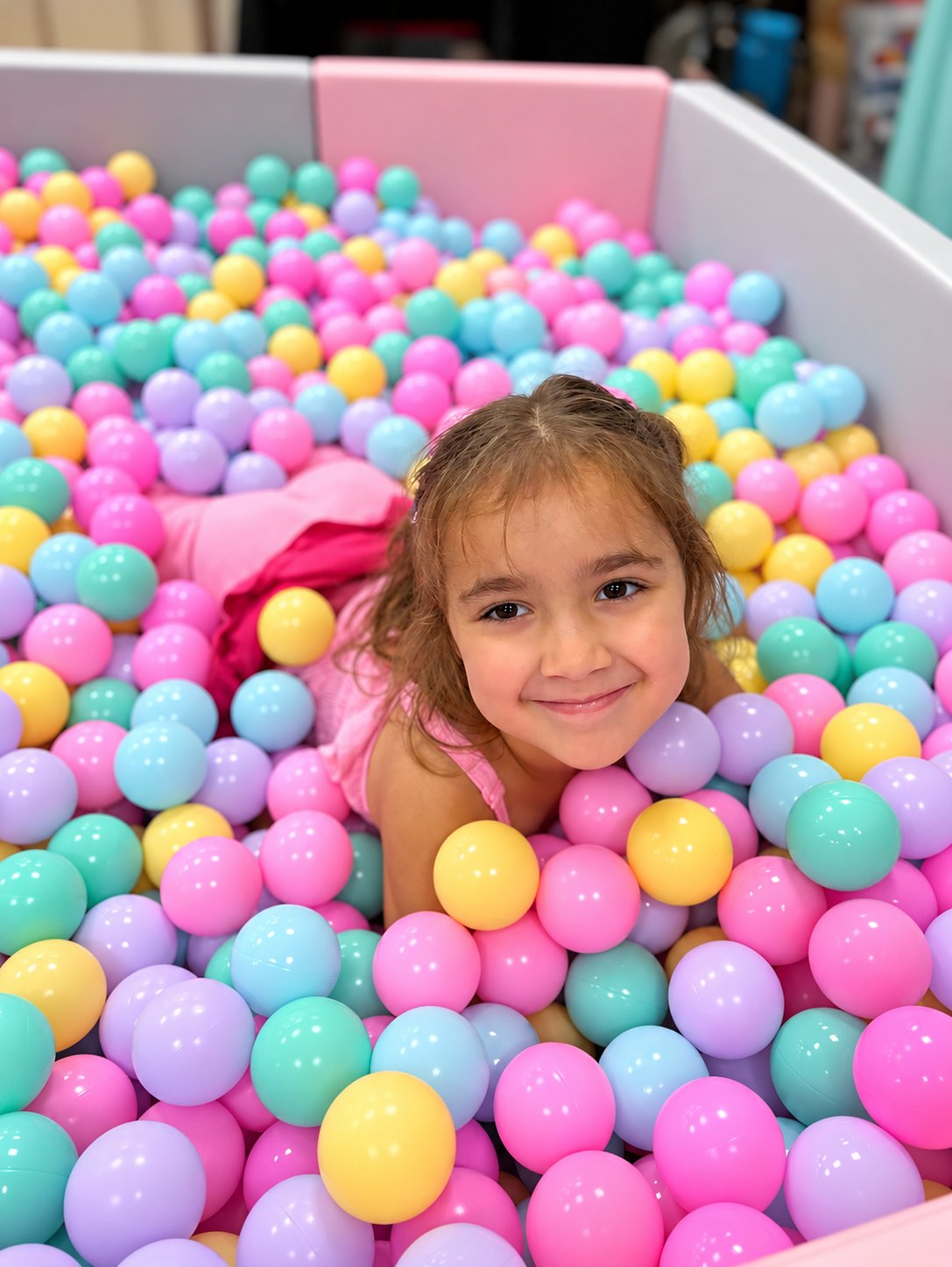 Girl playing in a large pastel ball pit