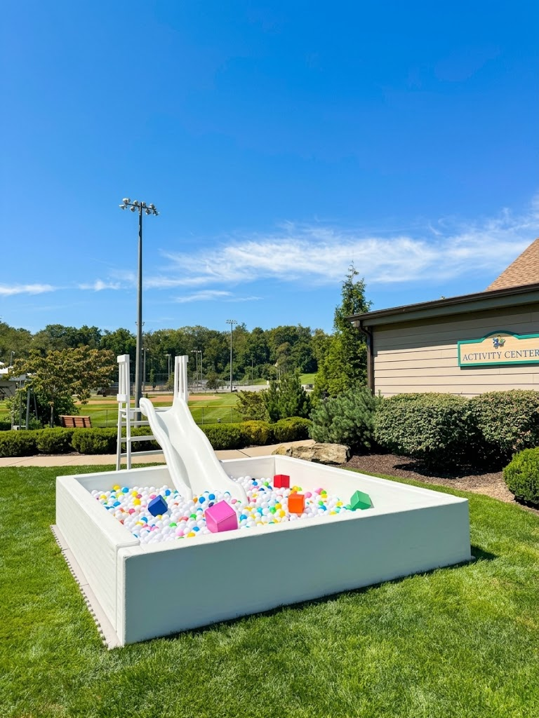 The white 10-foot ball pit filled with pastel balls and shown with a white slide on the lawn