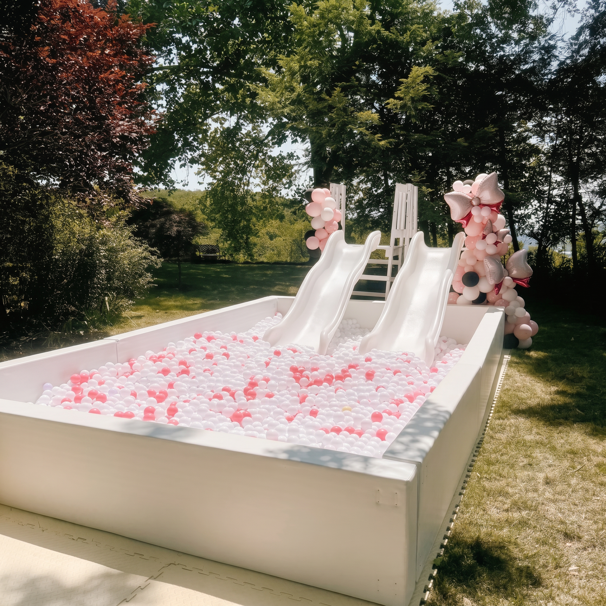 Little Harts luxury white ball pit with soft pink accents and balloon garland in a sunlit garden